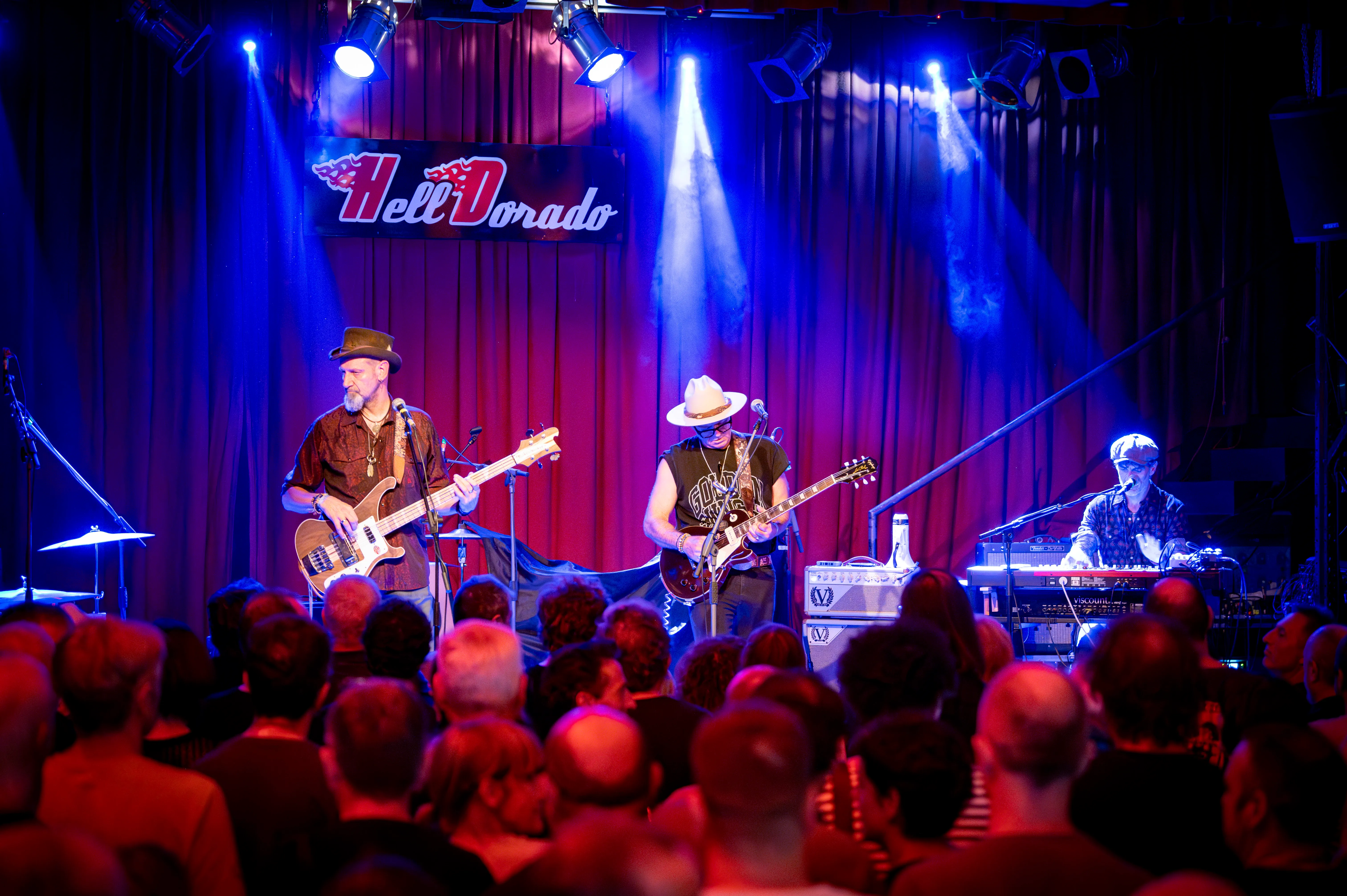 The band on stage under blue spotlights, seen over the heads of the crowd